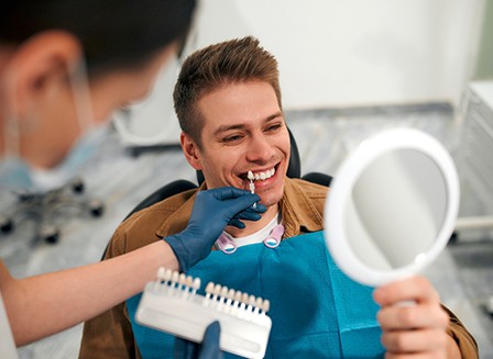 Dentist helping smiling patient select shade of veneers