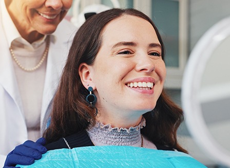 Woman with veneers smiling at reflection in mirror