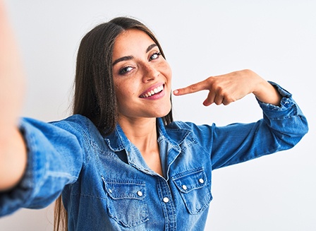 Smiling woman pointing to her white teeth