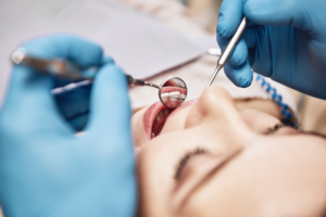 Dentist inspecting a patient’s teeth with a dental mirror