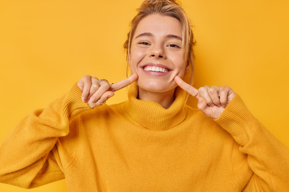 Woman in bright yellow turtle neck pointing at smile
